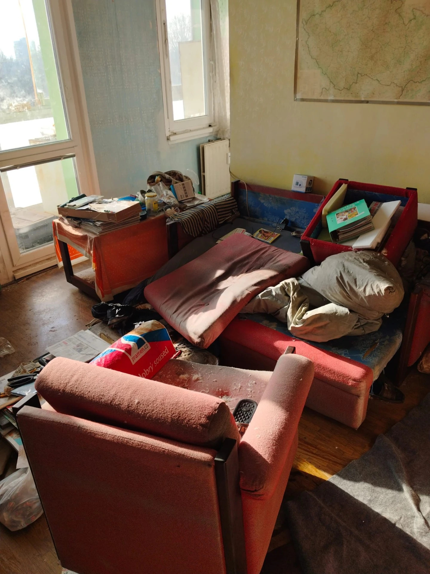 zanedbaný obývací pokoj s nábytkem a nepořádkem