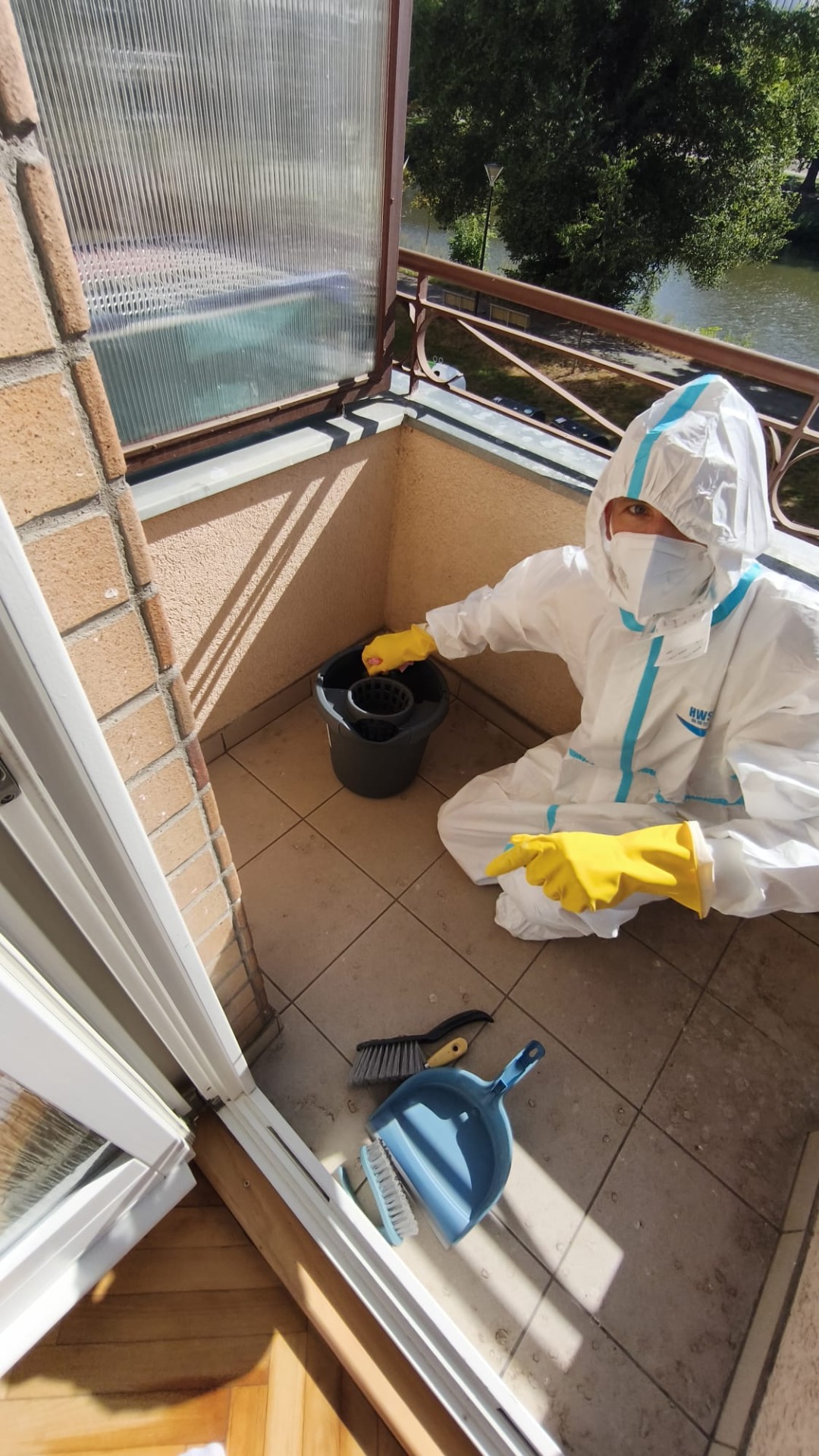 Pracovník v ochranném oděvu při čištění znečištěného balkonu